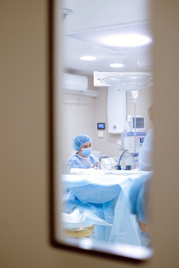 ours-journey View of a surgeon working in an operating room through a door window, emphasizing medical precision.